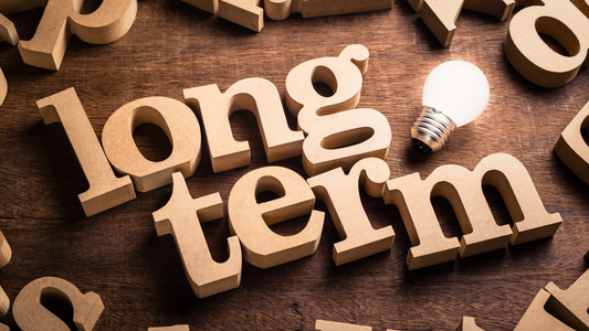 Brown background with letters in positions all around the outisde with a lightbulk next to the text 'Long Term' In big bubble writing in the middle