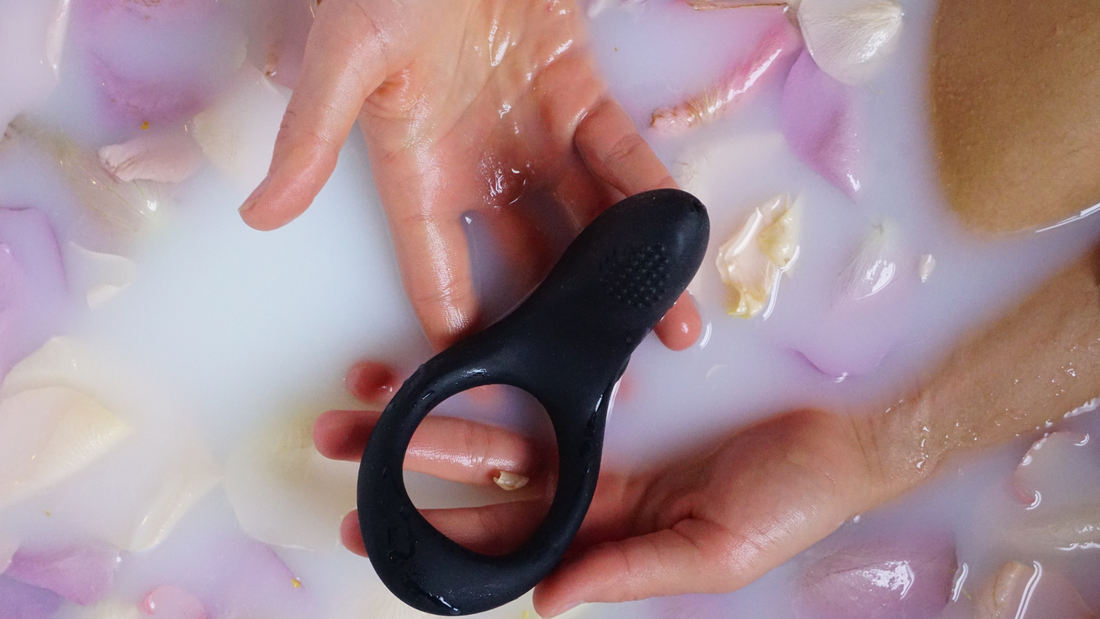 man holding vibrating cok ring under rose petal filled water