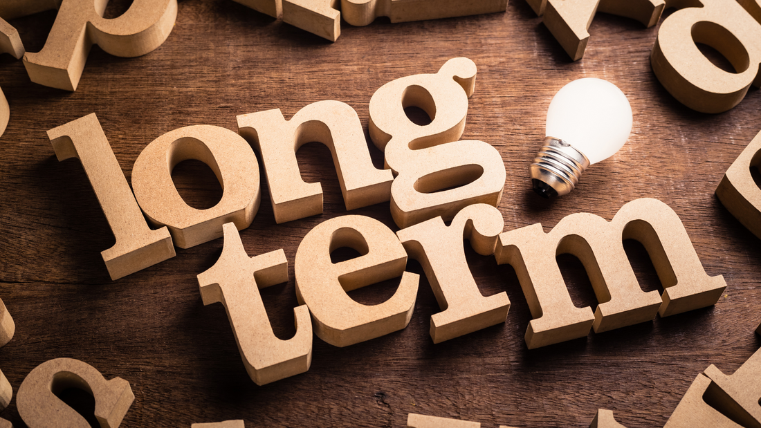 Brown background with letters in positions all around the outisde with a lightbulk next to the text 'Long Term' In big bubble writing in the middle