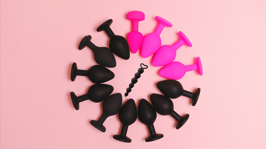Black and pink anal sex toys for men in a circle on pink background