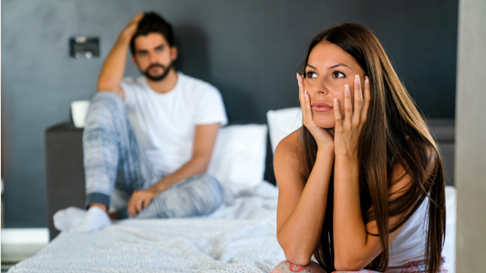 a couple sat on their bed looking stressed because of sub drop and dom drop