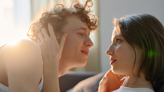 A couple talking in bed together with sunlight beaming through the curtains